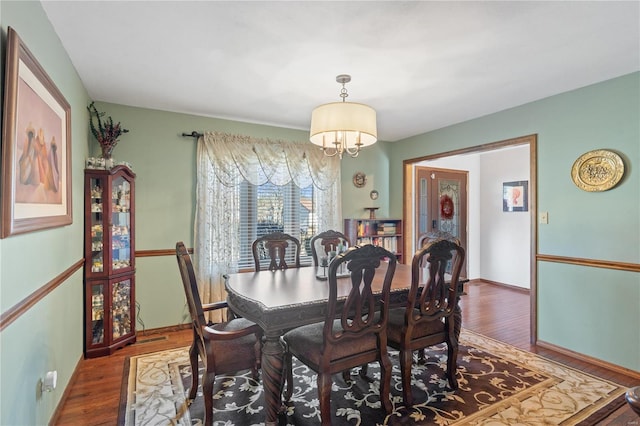 dining space featuring dark wood-type flooring and a chandelier