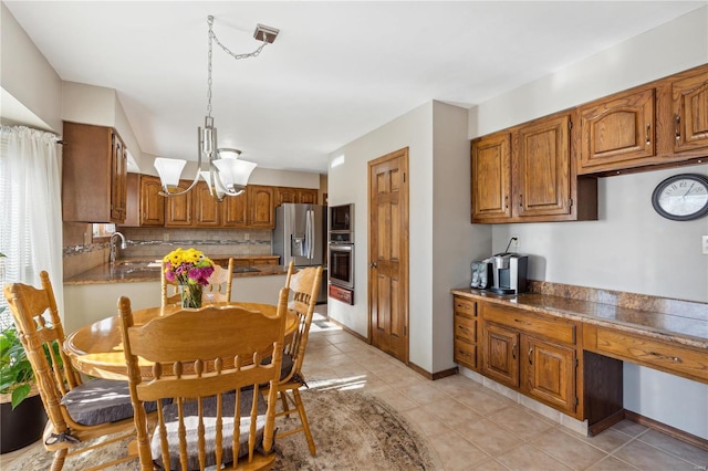 kitchen featuring appliances with stainless steel finishes, decorative light fixtures, sink, light tile patterned floors, and a notable chandelier