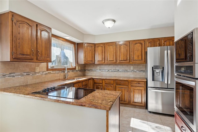 kitchen with light tile patterned flooring, appliances with stainless steel finishes, sink, decorative backsplash, and kitchen peninsula