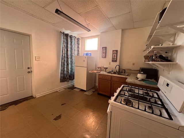 kitchen featuring white appliances, a paneled ceiling, and sink