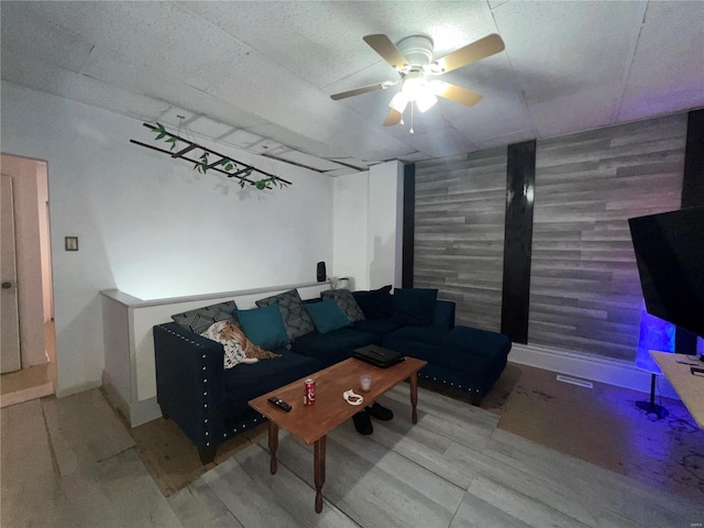 living room with ceiling fan and wood walls