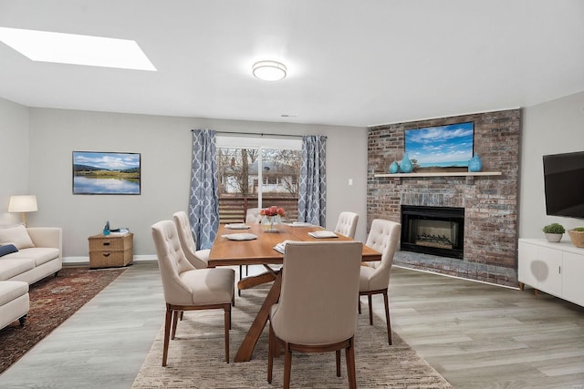 dining space with wood-type flooring and a brick fireplace