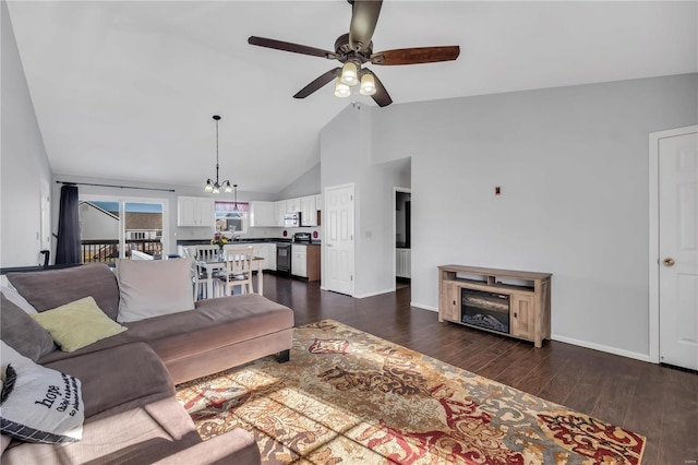 living room featuring vaulted ceiling, dark wood-type flooring, and ceiling fan with notable chandelier