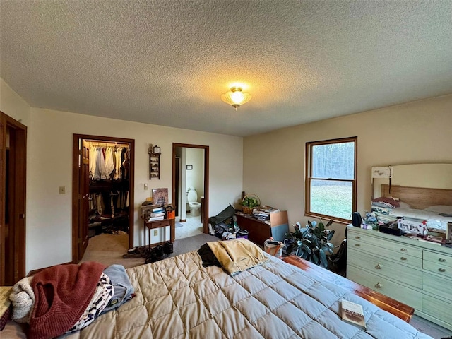 carpeted bedroom with a walk in closet, a closet, and a textured ceiling