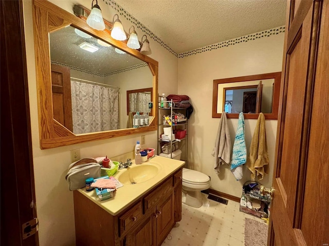 bathroom with vanity, curtained shower, toilet, and a textured ceiling