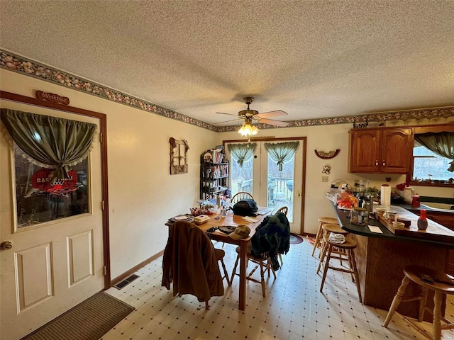 dining area featuring ceiling fan, a healthy amount of sunlight, and a textured ceiling