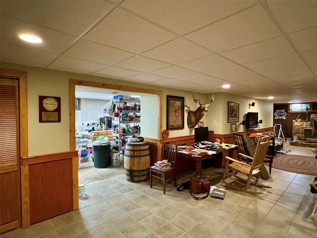 interior space featuring a paneled ceiling and wood walls