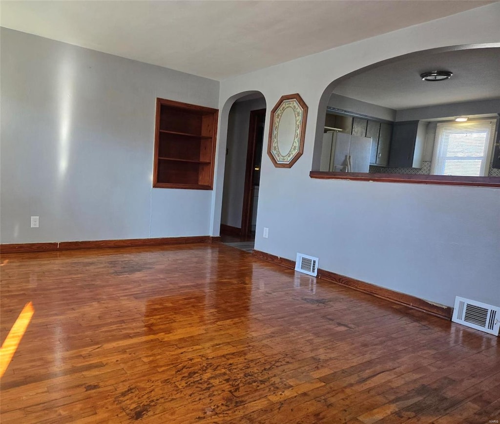 unfurnished room with built in features and dark wood-type flooring