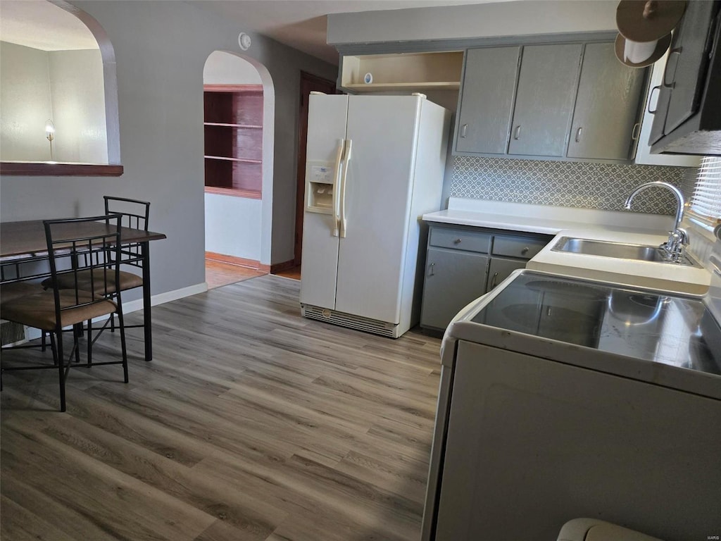 kitchen featuring gray cabinetry, sink, light hardwood / wood-style flooring, white refrigerator with ice dispenser, and range