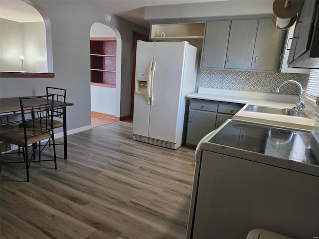 kitchen featuring gray cabinetry, sink, light hardwood / wood-style flooring, white refrigerator with ice dispenser, and range