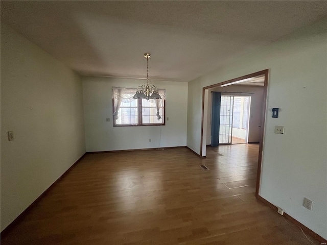 unfurnished dining area featuring an inviting chandelier and hardwood / wood-style floors