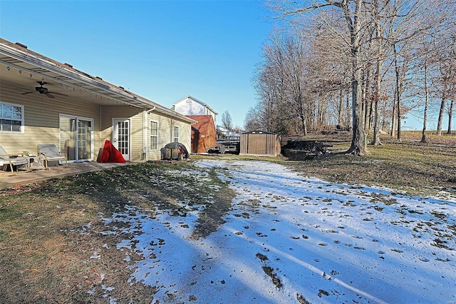 yard covered in snow featuring ceiling fan and a storage unit