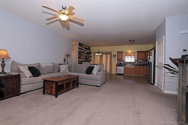 living room featuring ceiling fan, dark carpet, a textured ceiling, and sink