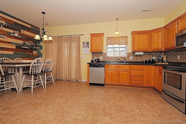 kitchen with decorative backsplash, pendant lighting, stainless steel appliances, and a notable chandelier