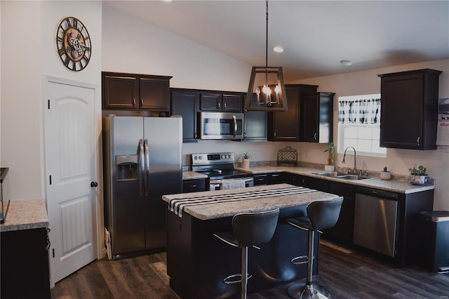 kitchen with hanging light fixtures, stainless steel appliances, a kitchen island, dark hardwood / wood-style flooring, and sink