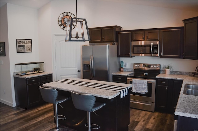 kitchen featuring a breakfast bar area, appliances with stainless steel finishes, a kitchen island, dark hardwood / wood-style floors, and decorative light fixtures