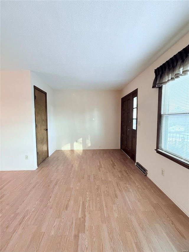 unfurnished living room featuring a textured ceiling and light hardwood / wood-style floors