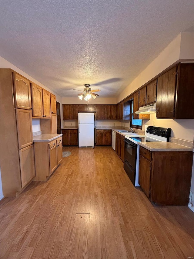 kitchen featuring sink, white appliances, light hardwood / wood-style flooring, ceiling fan, and a textured ceiling