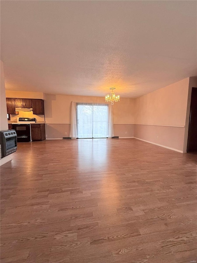 unfurnished living room featuring an inviting chandelier, hardwood / wood-style floors, and a textured ceiling