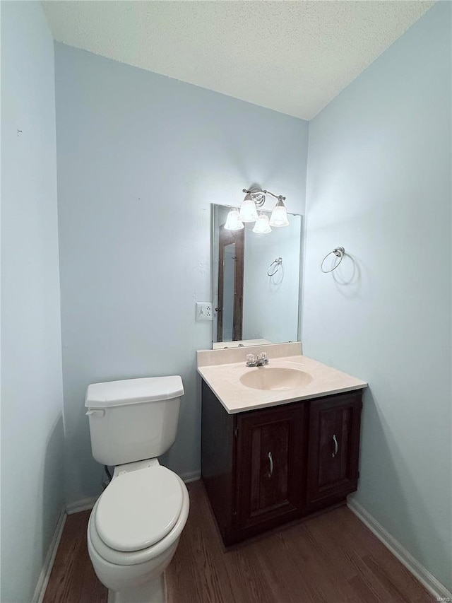 bathroom featuring hardwood / wood-style flooring, vanity, toilet, and a textured ceiling