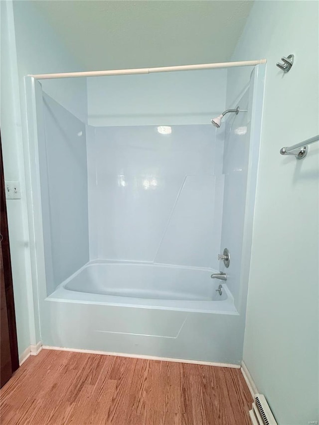 bathroom with wood-type flooring, bathtub / shower combination, and a baseboard heating unit