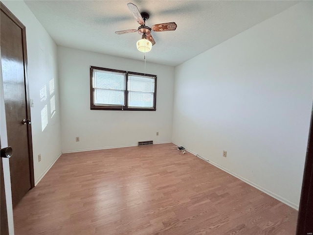 empty room with ceiling fan, light hardwood / wood-style flooring, and a textured ceiling