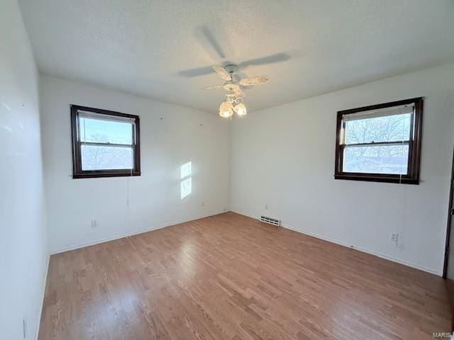 empty room featuring ceiling fan, light hardwood / wood-style floors, and a textured ceiling