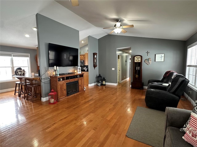 living room with hardwood / wood-style floors, vaulted ceiling, and ceiling fan