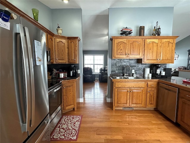 kitchen featuring backsplash, light hardwood / wood-style floors, sink, and appliances with stainless steel finishes