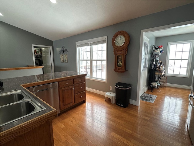 kitchen with dishwasher, light hardwood / wood-style floors, vaulted ceiling, and sink