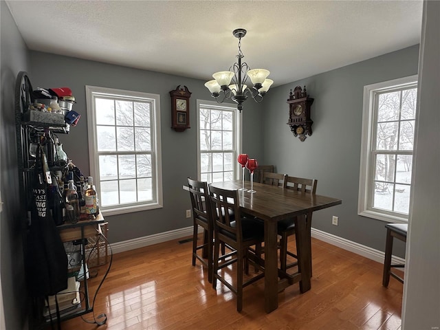 dining area with a healthy amount of sunlight, a chandelier, and wood-type flooring