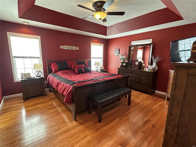 bedroom featuring a tray ceiling, light hardwood / wood-style flooring, and ceiling fan