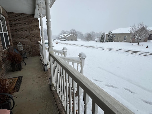 snow covered back of property with covered porch