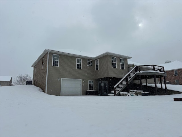 snow covered house featuring a garage and a deck