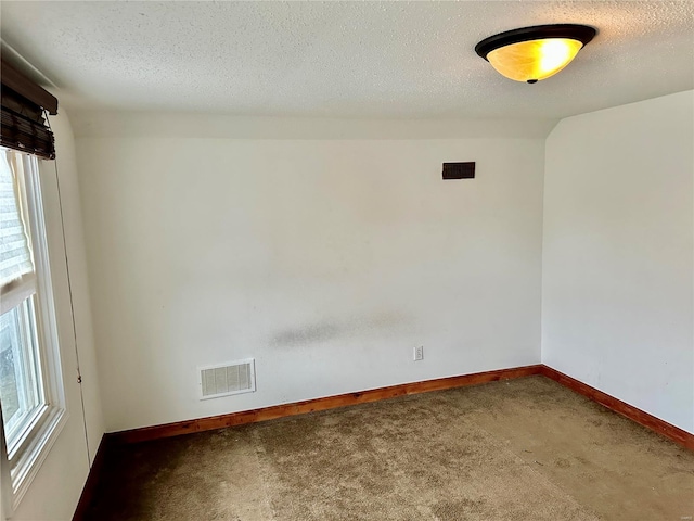 carpeted empty room featuring a textured ceiling