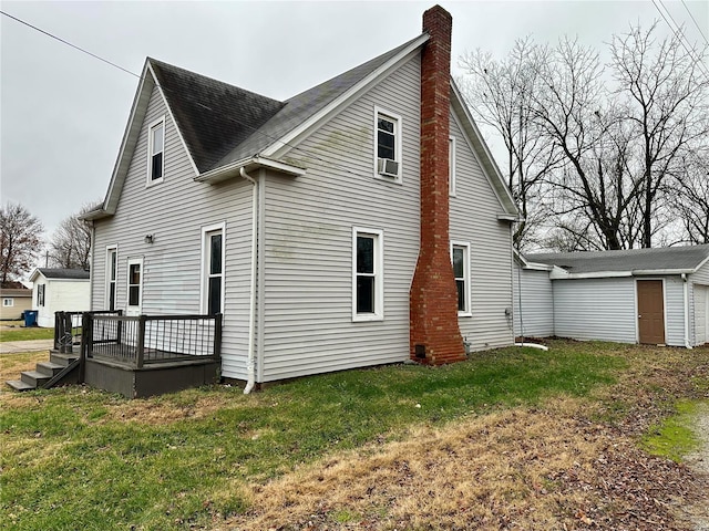 back of property with a yard, a wooden deck, an outdoor structure, and a chimney