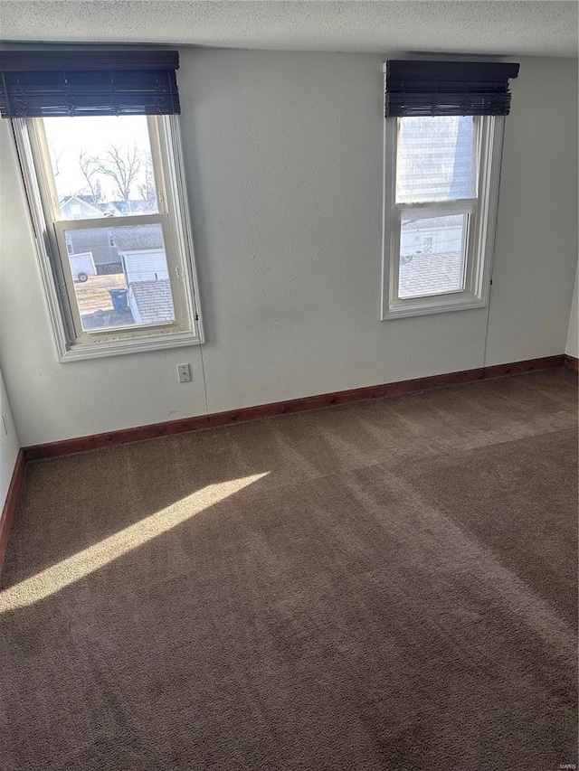 unfurnished room featuring a healthy amount of sunlight, baseboards, carpet floors, and a textured ceiling