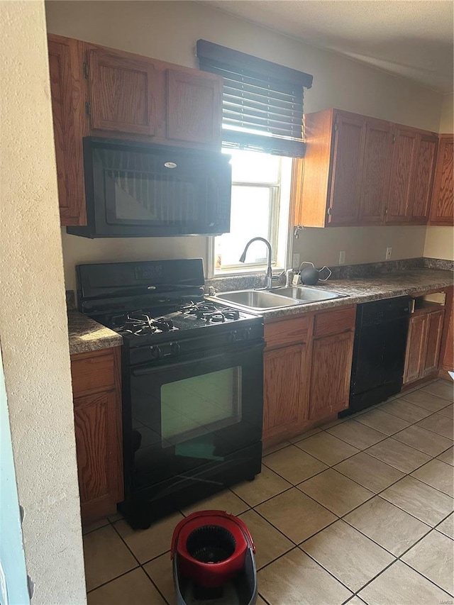 kitchen with light tile patterned floors, brown cabinets, black appliances, and a sink