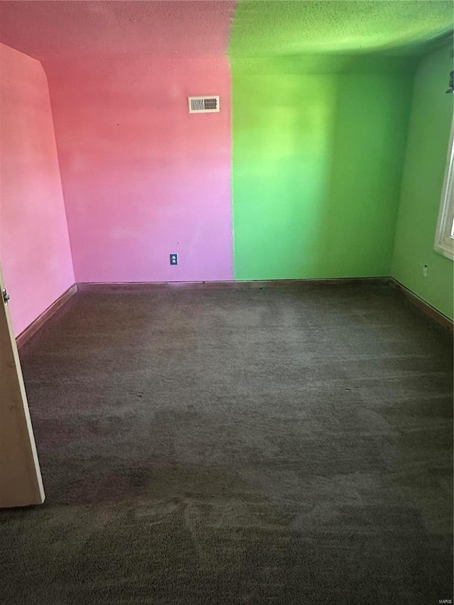 empty room featuring visible vents, carpet floors, and a textured ceiling