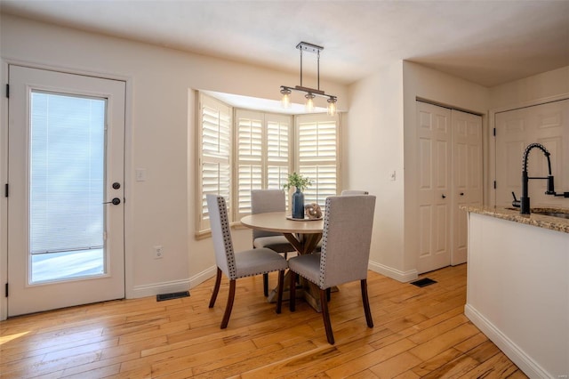 dining space featuring light wood-type flooring and sink