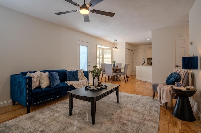 living room with ceiling fan, sink, and light hardwood / wood-style floors