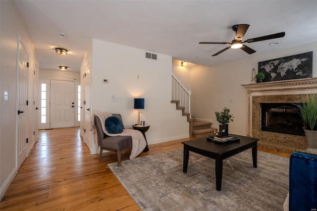 living room featuring ceiling fan, light hardwood / wood-style floors, and a fireplace