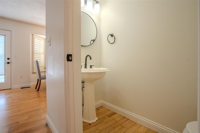 bathroom with hardwood / wood-style floors, toilet, and a wealth of natural light