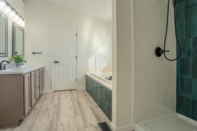 bathroom with a tile shower, vanity, and hardwood / wood-style flooring