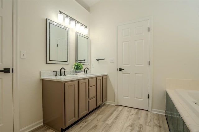 bathroom featuring hardwood / wood-style floors, vanity, and tiled bath