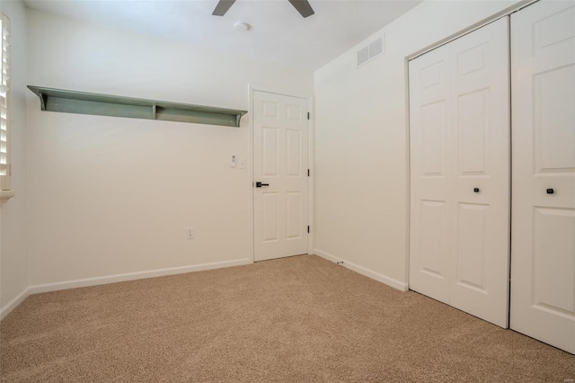 unfurnished bedroom with ceiling fan, light carpet, and a closet