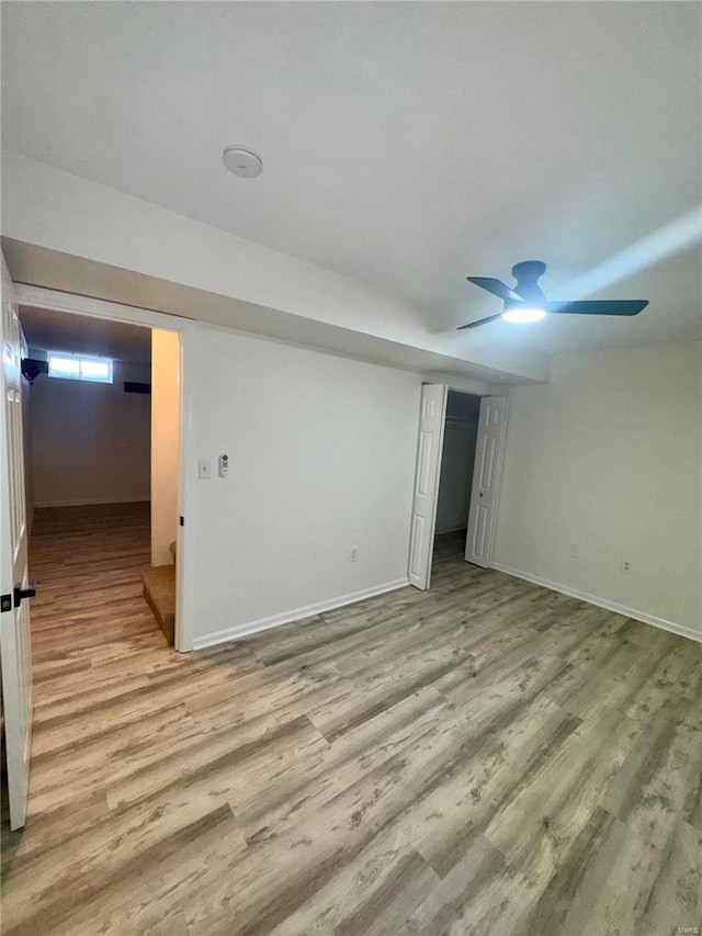 unfurnished bedroom with ceiling fan, a closet, a spacious closet, and light wood-type flooring