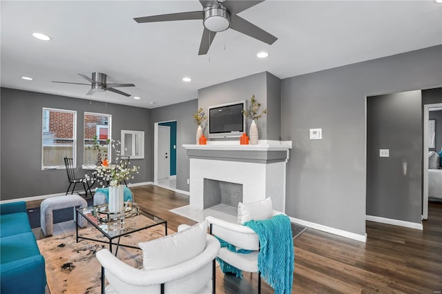 living room with ceiling fan, a fireplace, and dark hardwood / wood-style floors