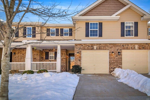 view of front of property featuring brick siding, a porch, an attached garage, and driveway