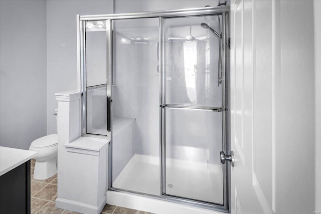 bathroom with toilet, vanity, and a shower with shower door